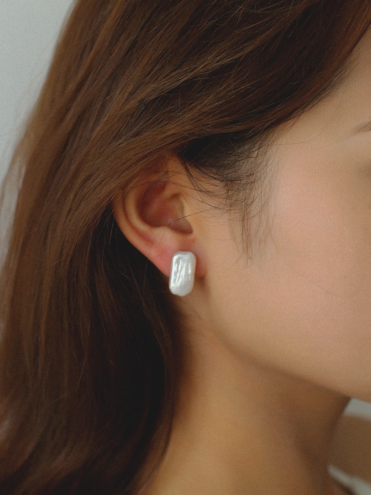 Close-up of an ear wearing a silver earring with a blurred background from Gembee Jewellery