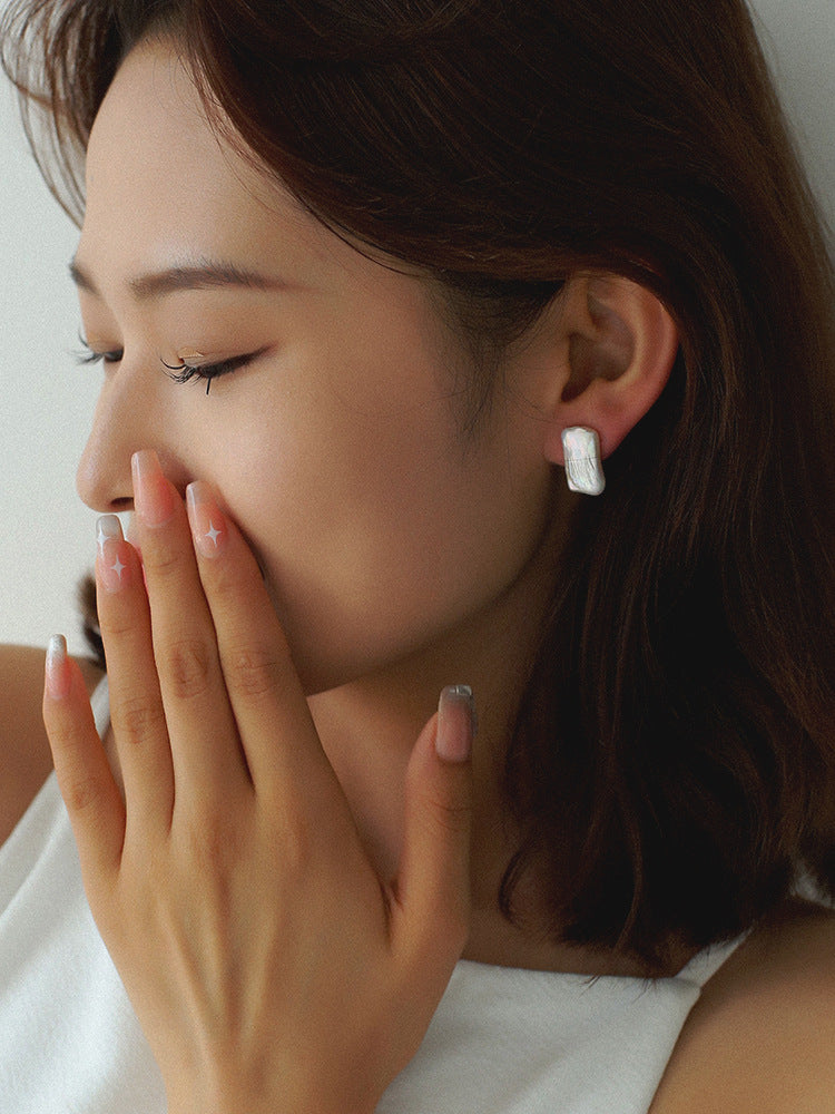 Close-up of a woman wearing a white earring with a blurred background from Gembee Jewellery