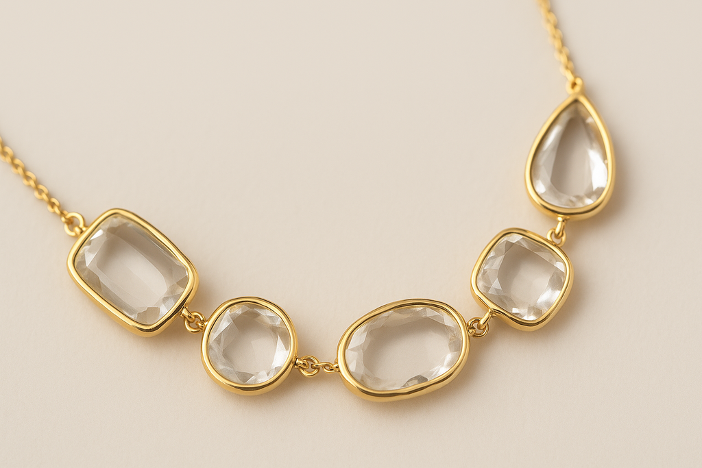 Gold bracelets with clear stone pendants on a beige background