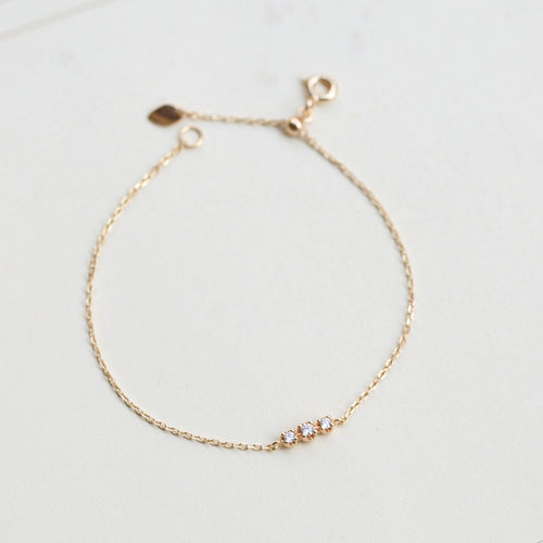 Gold bracelet with small stones on a light gray background from the GemBee Jewellery.
