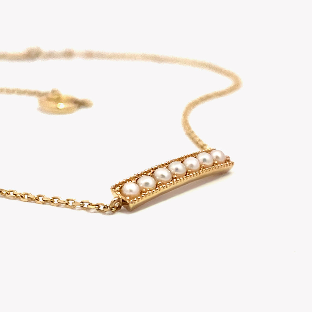 Gold necklace with a bar pendant featuring pearls on a white background from Gembee JEwellery