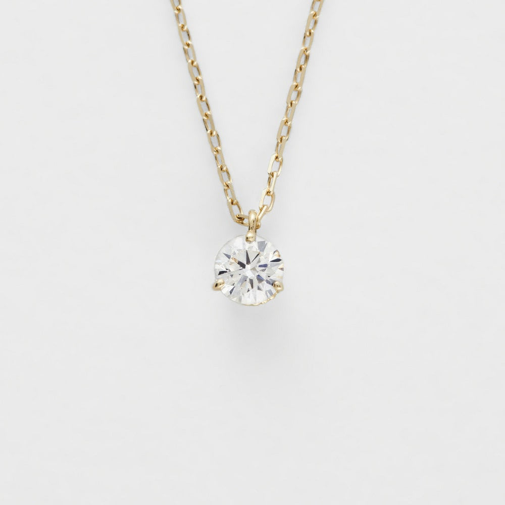 Gold necklace with a clear gemstone pendant on a light gray background