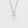 Gold necklace with a clear gemstone pendant on a light gray background