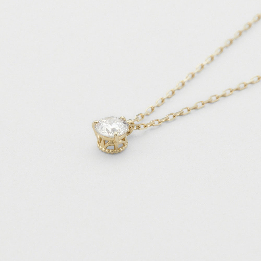 Gold necklace with a clear gemstone on a light gray background