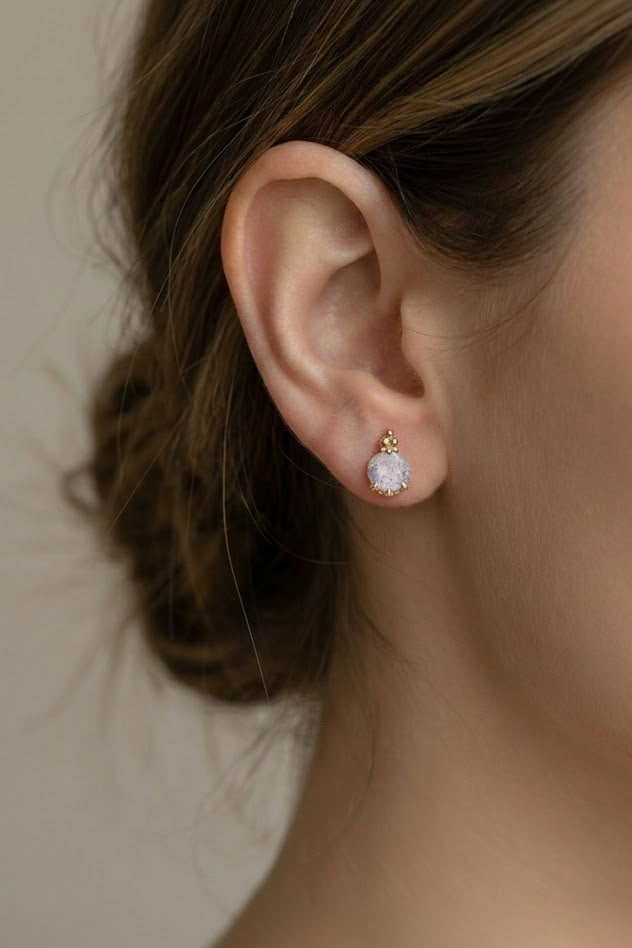 Close-up of an ear wearing a labradorite earring with a blurred background