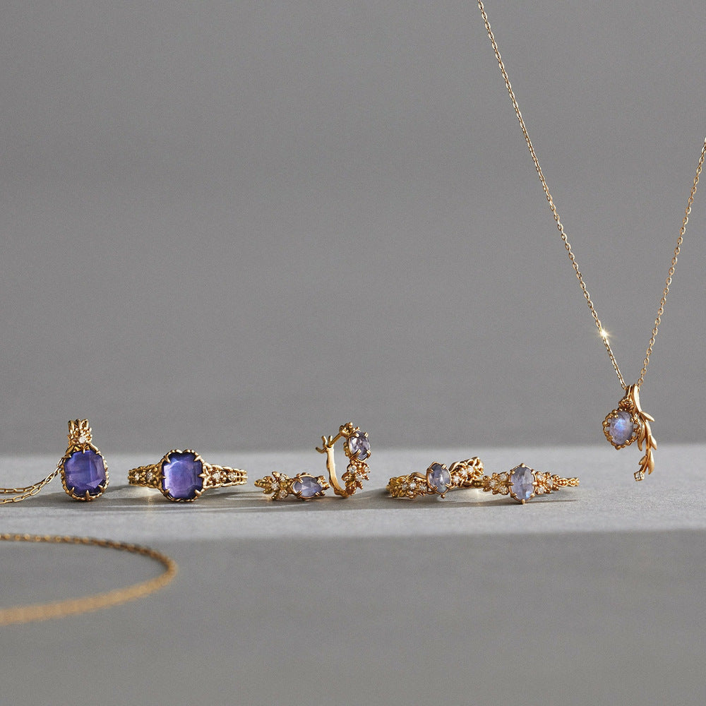 Gold jewelry set with purple gemstones on a gray background