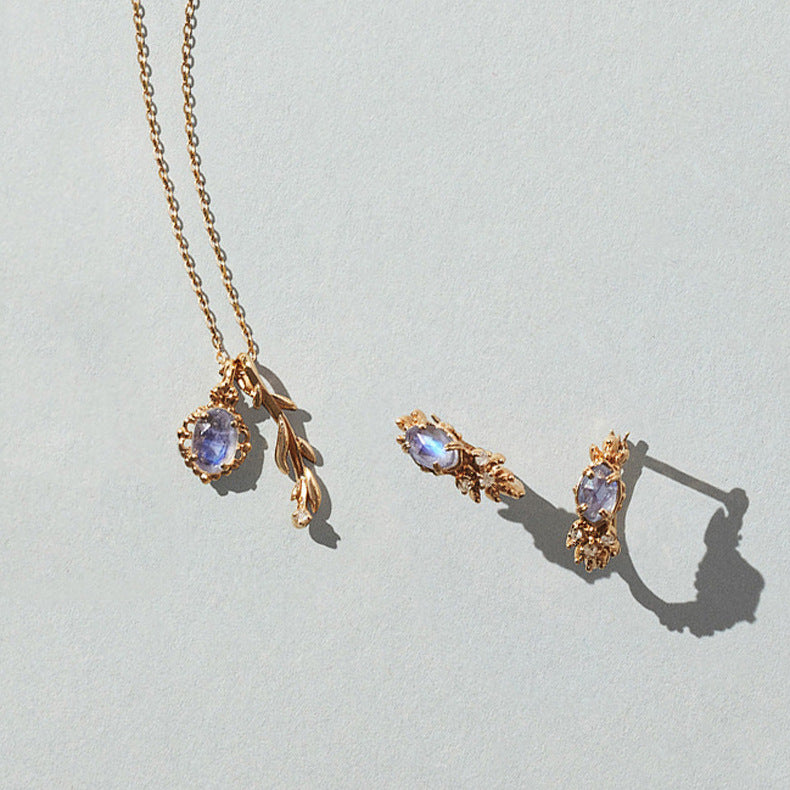 Gold jewelry set with gemstones on a light gray background