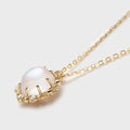 Close-up of a natural moonstone pendant with creamy-blue glow, set in gold-plated 925 silver claw design on a fine chain.