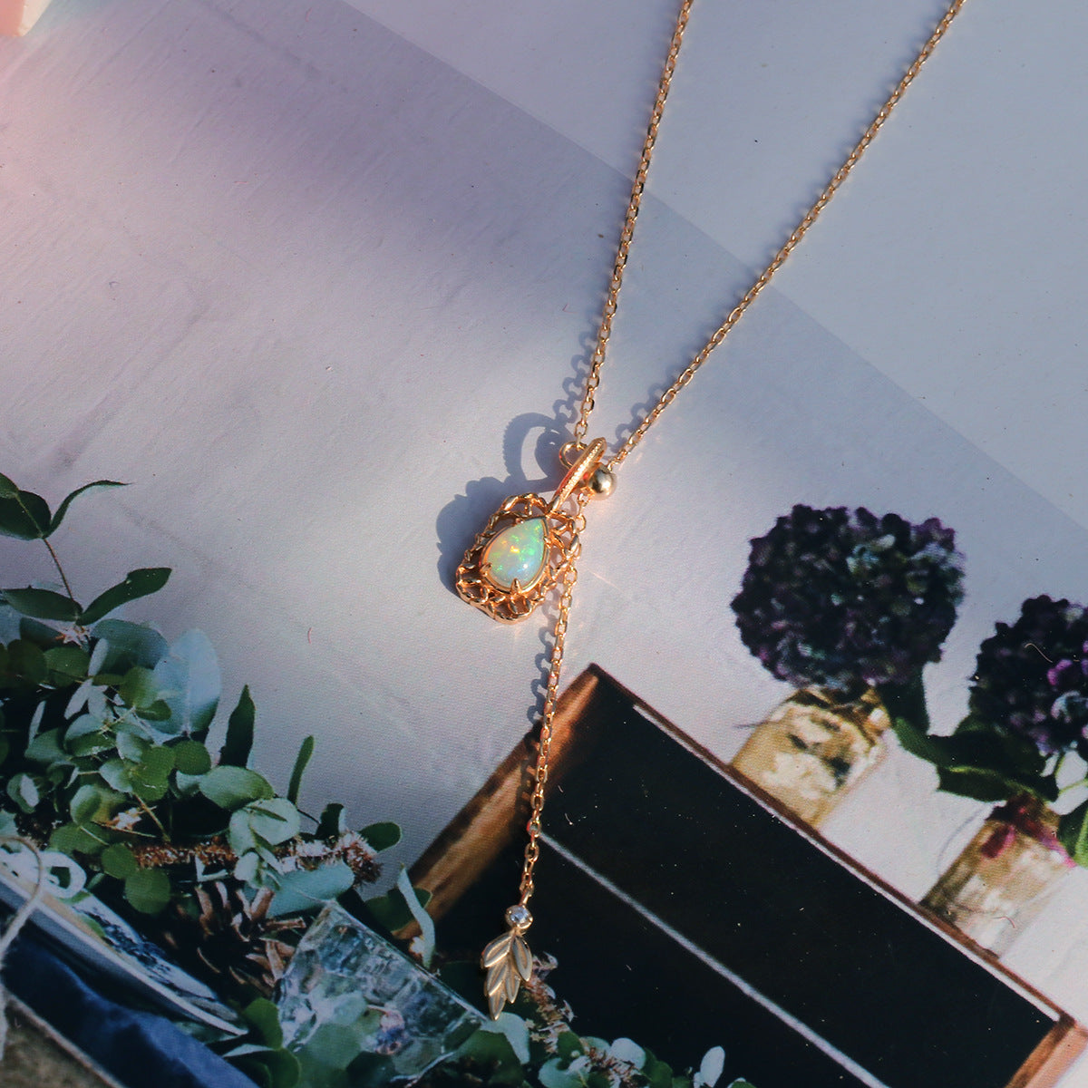 Natural opal pear-shaped pendant styled with a gold lariat necklace