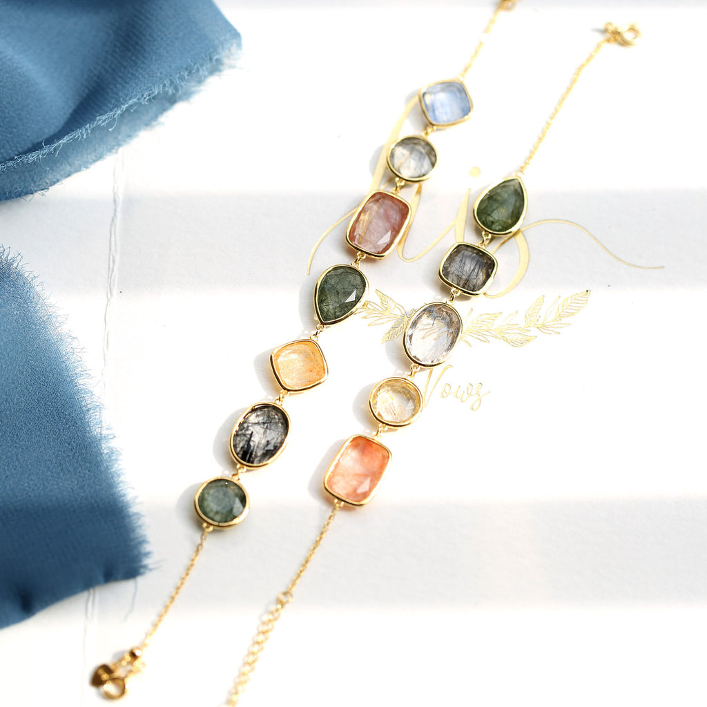 Jewelry set with multicolored stones and gold chains on a white background