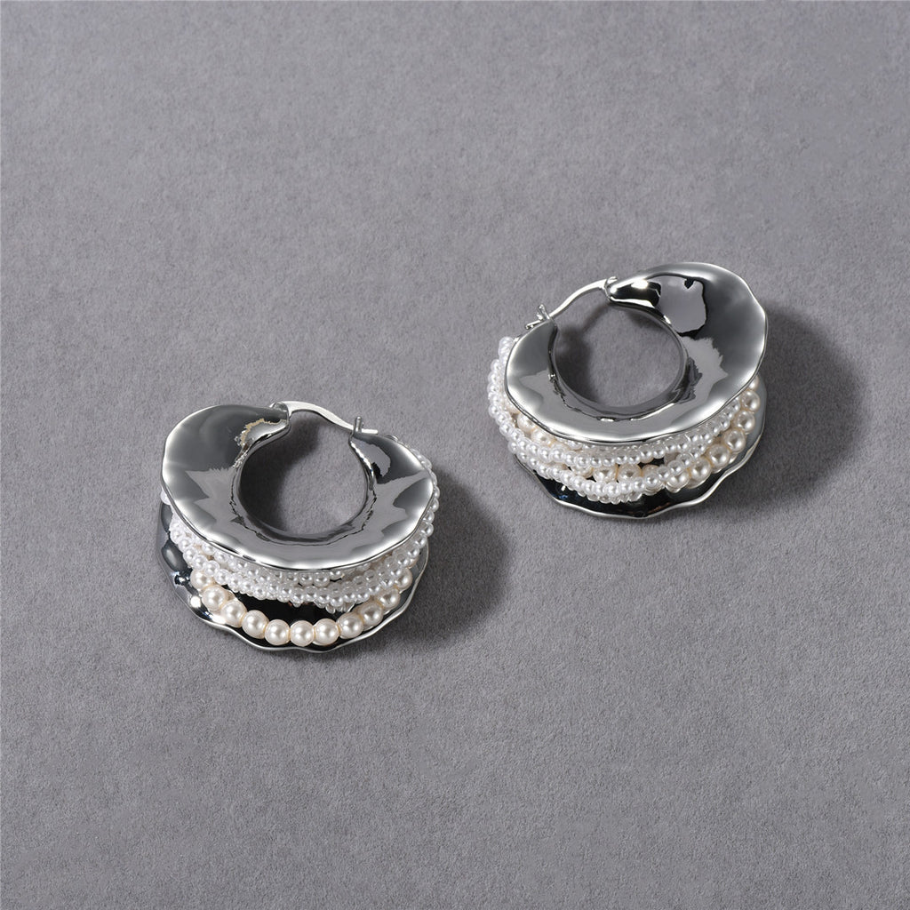 Pair of silver hoop earrings with pearl accents on a gray background