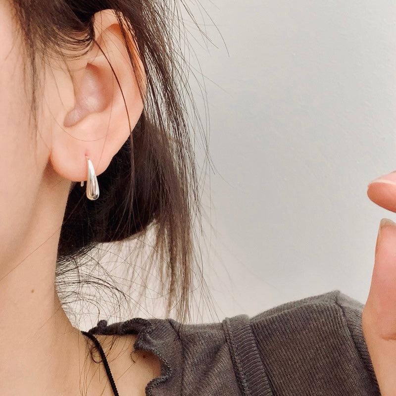 Close-up of an ear wearing a silver hoop earring with a blurred background From Gembee Jewellery