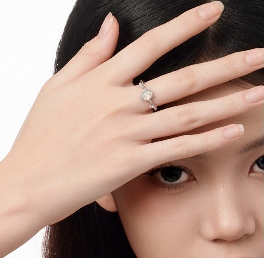 Close-up of a hand wearing an engagement ring with a blurred background from Gembee Jewellery