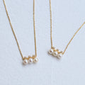 Two pearl necklaces on gold chains against a light blue background from Gembee Jewellery