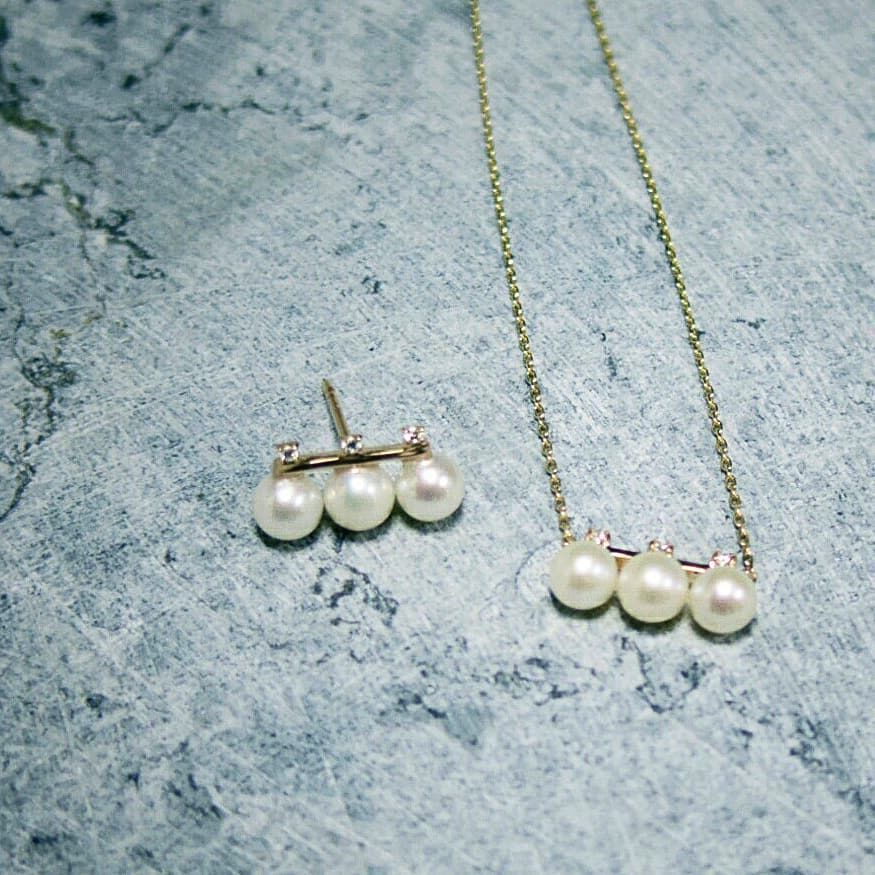 Pearl necklace and earrings on a textured gray surface from Gembee Jewellery