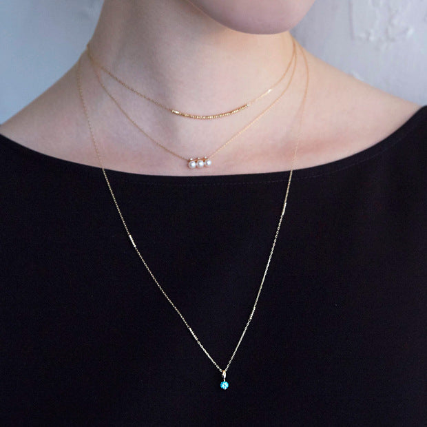 Two gold necklaces on a person from Gembee Jewellery