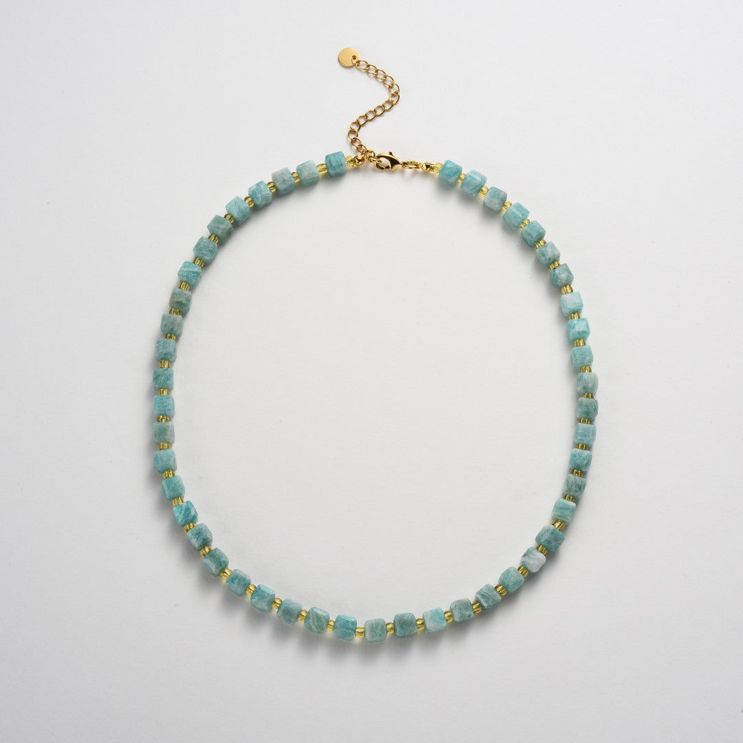 Necklace with blue beads and gold accents on a light gray background