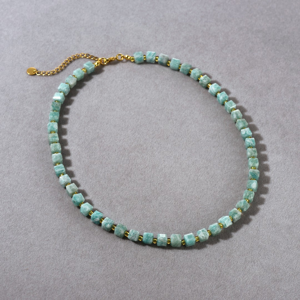 Necklace with turquoise beads and gold chain on a gray background