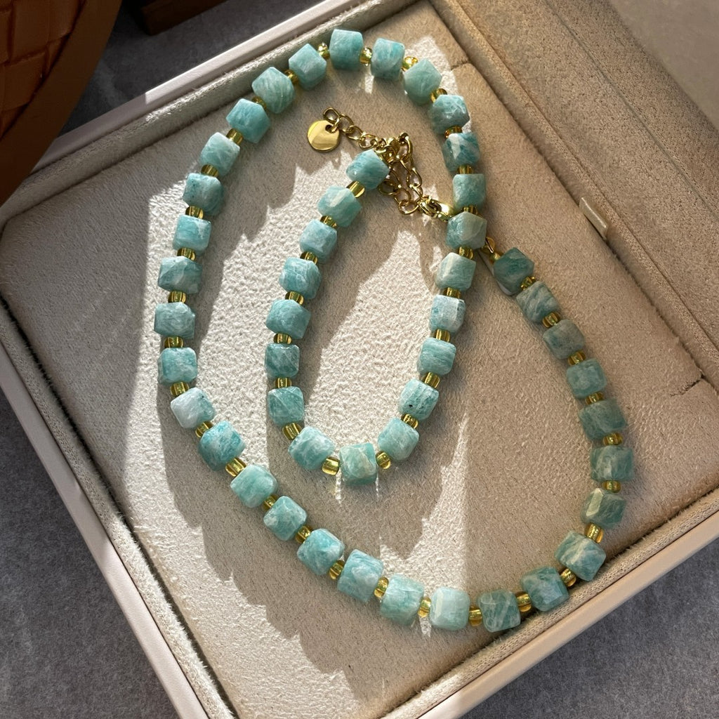 Turquoise beaded necklace with gold accents on a textured surface