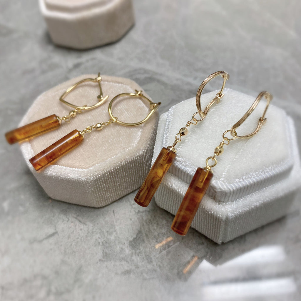 Pair of gold and amber bar earrings on a white jewelry display block from  the GemBee Jewellery