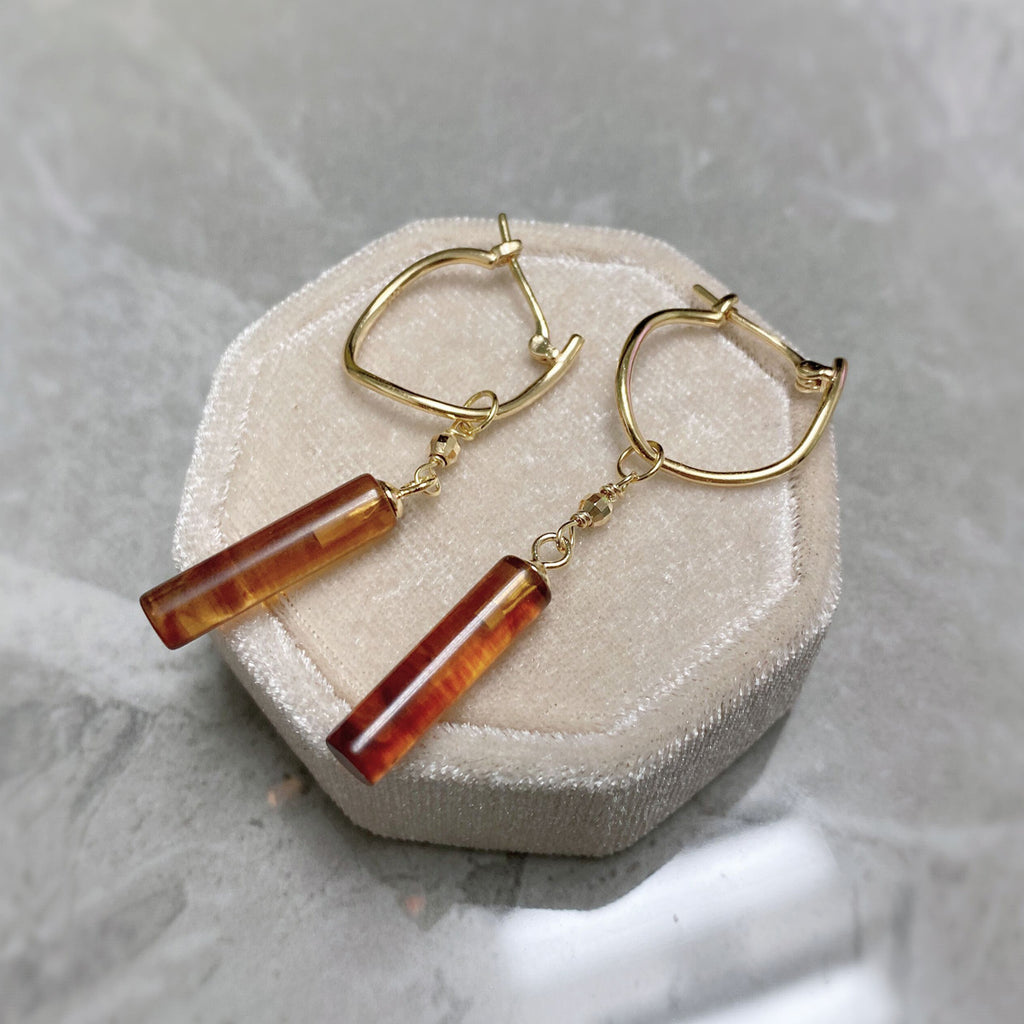 Gold hoop earrings with amber-colored bar pendants on a textured surface from  the GemBee Jewellery
