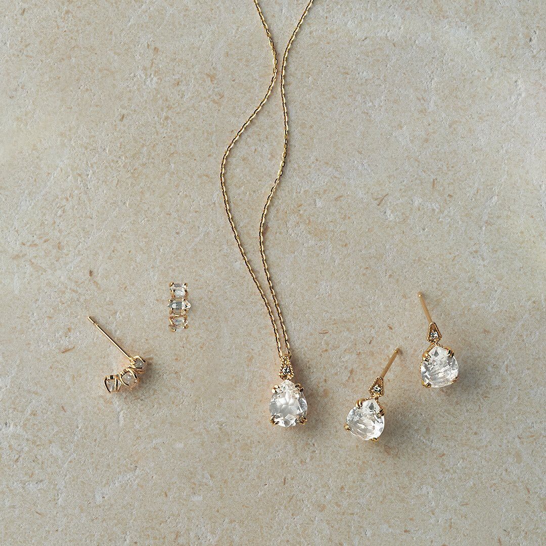Gold jewelry set with necklace, ring, and earrings on a beige surface from the Gembee Jewellery.