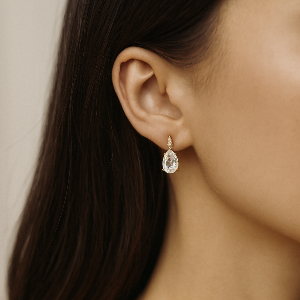 Close-up of a woman's ear wearing a teardrop-shaped diamond earring from the Gembee Jewellery.